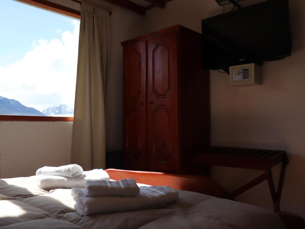 a bedroom with two towels on a bed with a window at Kalenshen in El Chalten