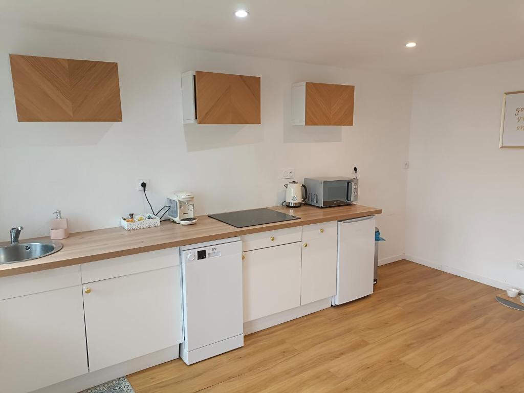 a kitchen with white cabinets and a sink at La Maison de Juliette maison entière avec garage et terrain in Condé-sur-Sarthe