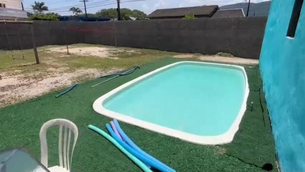 een klein zwembad met groen gras naast een hek bij 200m da Praia, Piscina Itanhaém in Itanhaém