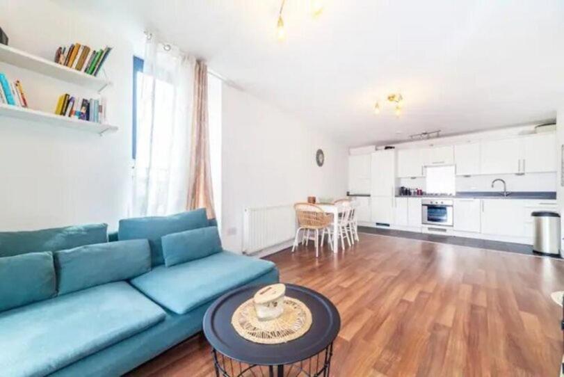 uma sala de estar com um sofá azul e uma mesa em Charming 2 Bed flat near Greenwich em Londres