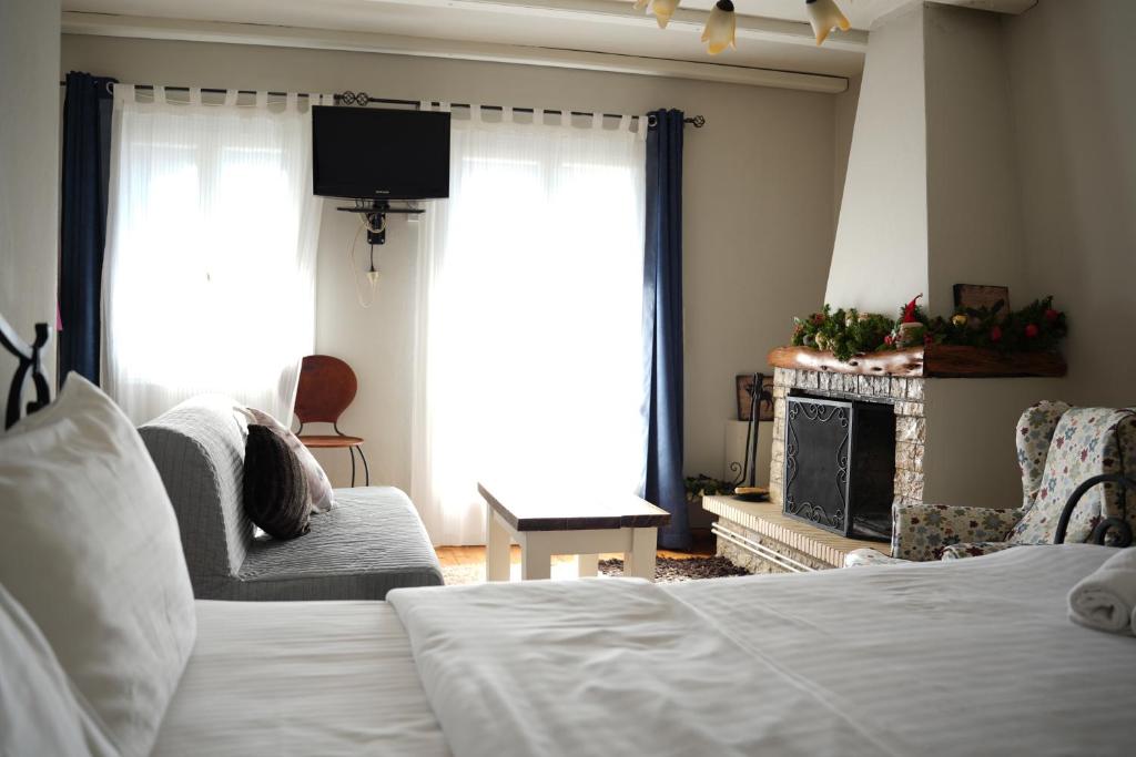 Guesthouse Doma في أراخوفا: غرفة معيشة مع سرير ومدفأة