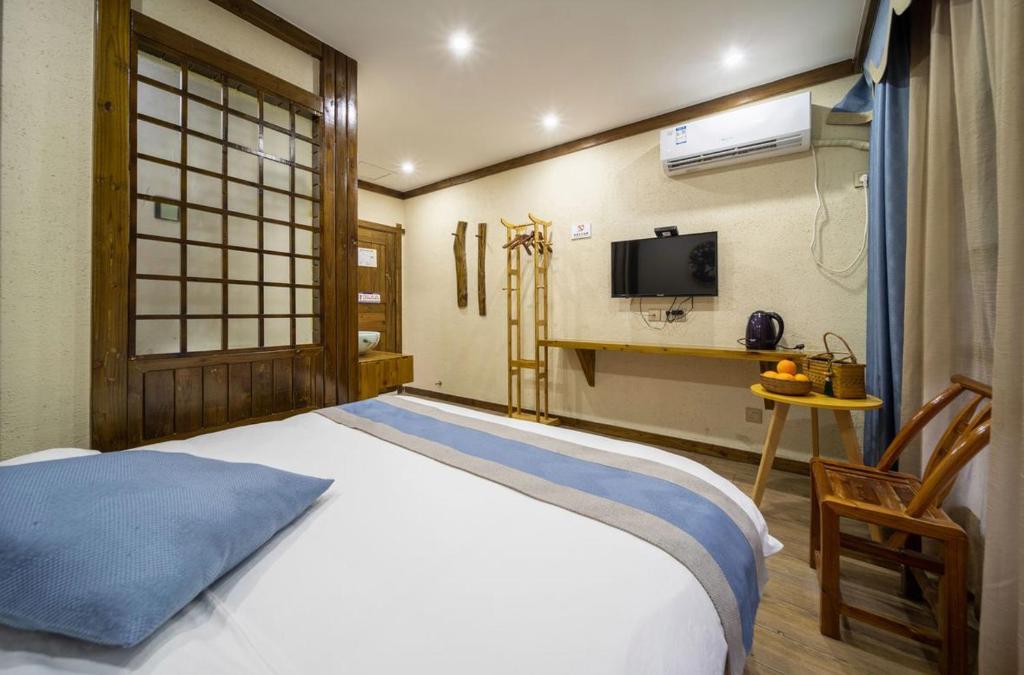 1 dormitorio con 1 cama, TV y ventana en Mountains Beyond Mountains Inn en Zhangjiajie