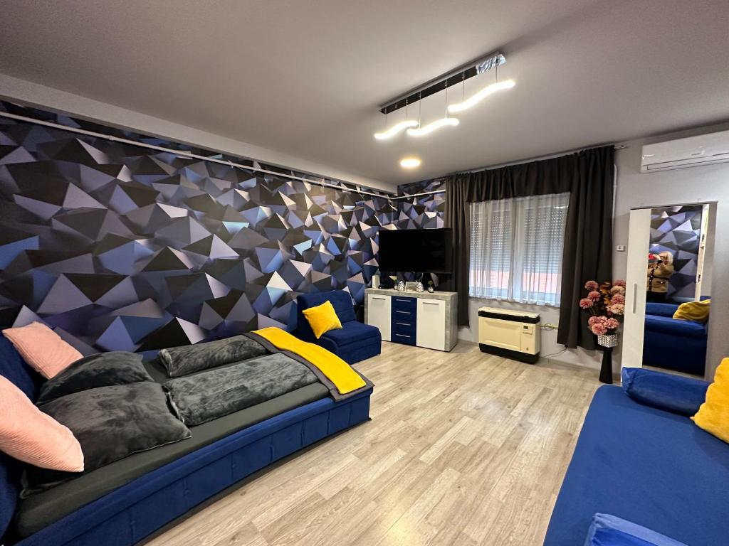 a living room with a blue couch and a tv at Kitty Downtown Apartman in Debrecen