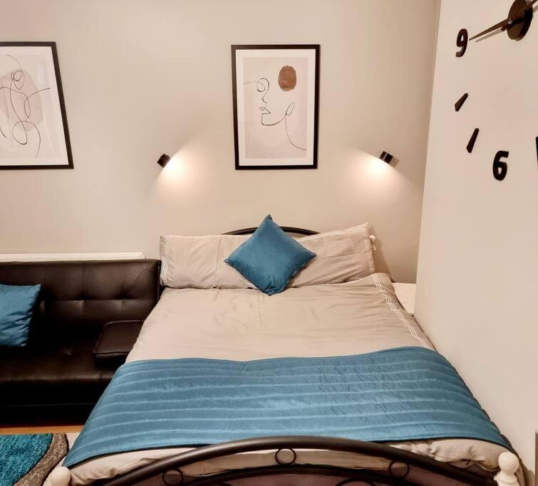 1 dormitorio con cama y sofá de cuero en Stylish Apartment, self check-in, 25mins to Gatwick Airport, en Thornton Heath