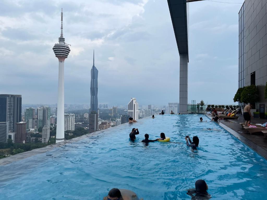 un grupo de personas en una piscina infinita en la parte superior de un edificio en The Platinum KLCC By Victoria Home en Kuala Lumpur