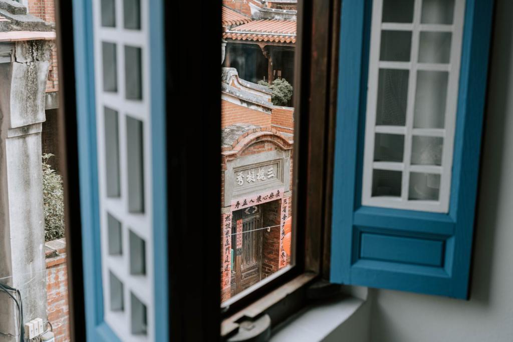 une fenêtre ouverte avec vue sur un bâtiment dans l'établissement 鹿港老街十三號民宿, à Lukang