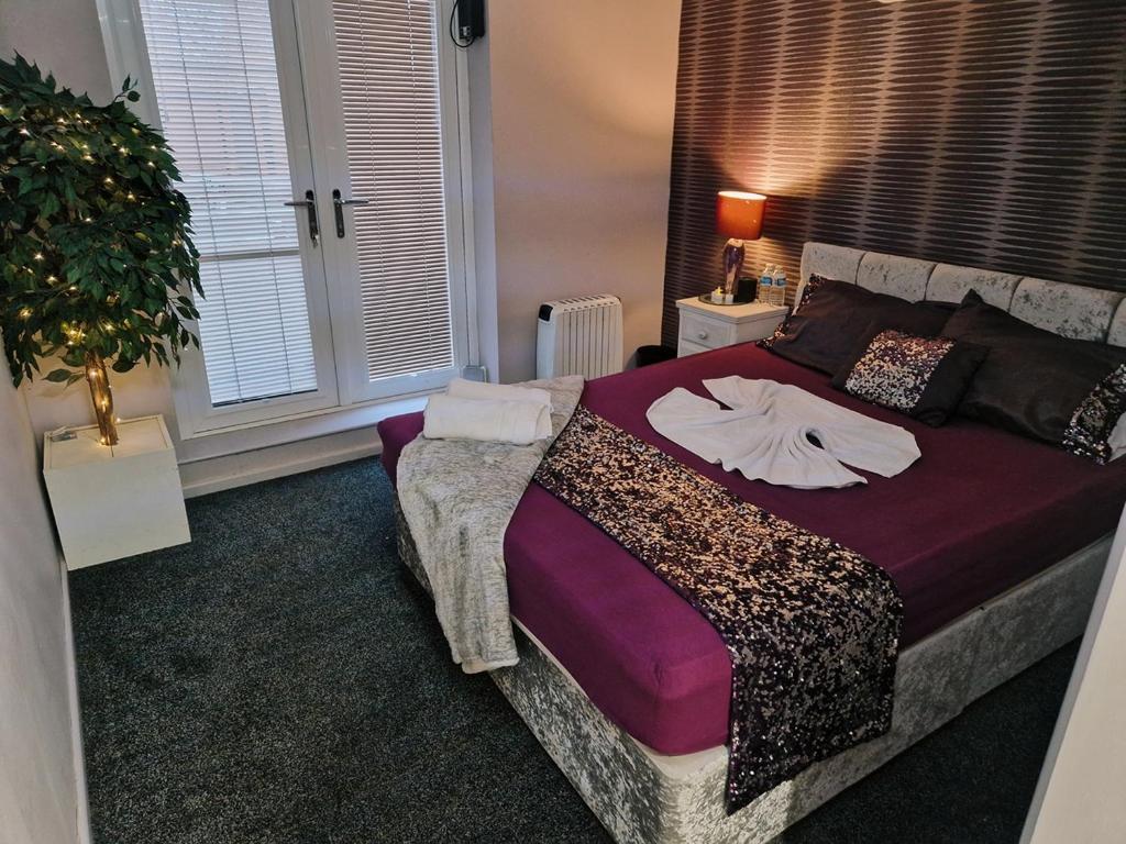 um quarto com uma cama grande com lençóis e almofadas roxos em Unit 8 Adult Lovers Hotel em Handsworth