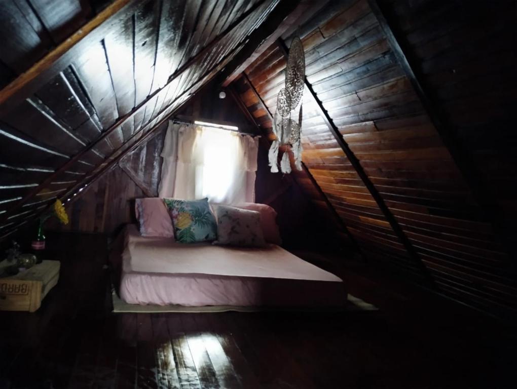 uma pequena cama num quarto de madeira com uma janela em Chalé simples em camping com bastante movimento em Atibaia