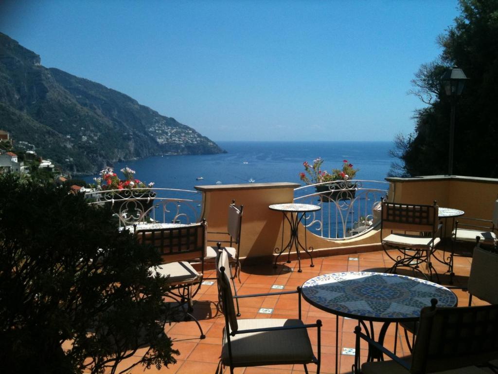 un patio con tavoli, sedie e vista sull'oceano di Hotel Posa Posa a Positano