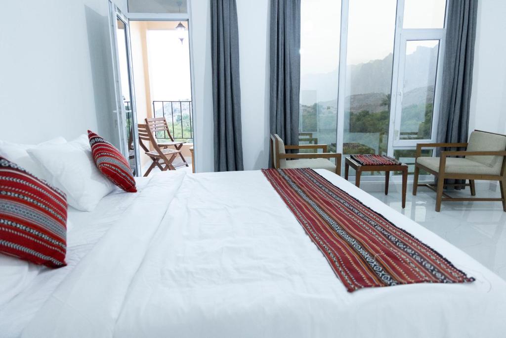 a bedroom with a large white bed with red pillows at Hadash guest house in Ghubrah