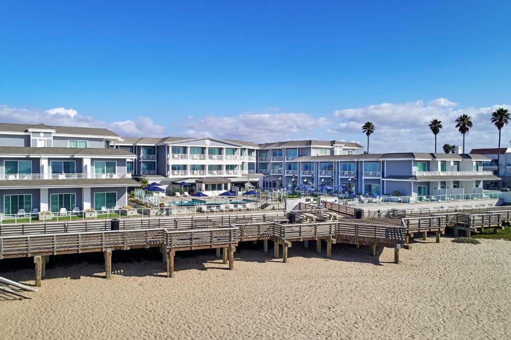 a row of wooden benches on a beach with buildings at Vespera Resort on Pismo Beach, Autograph Collection in Pismo Beach