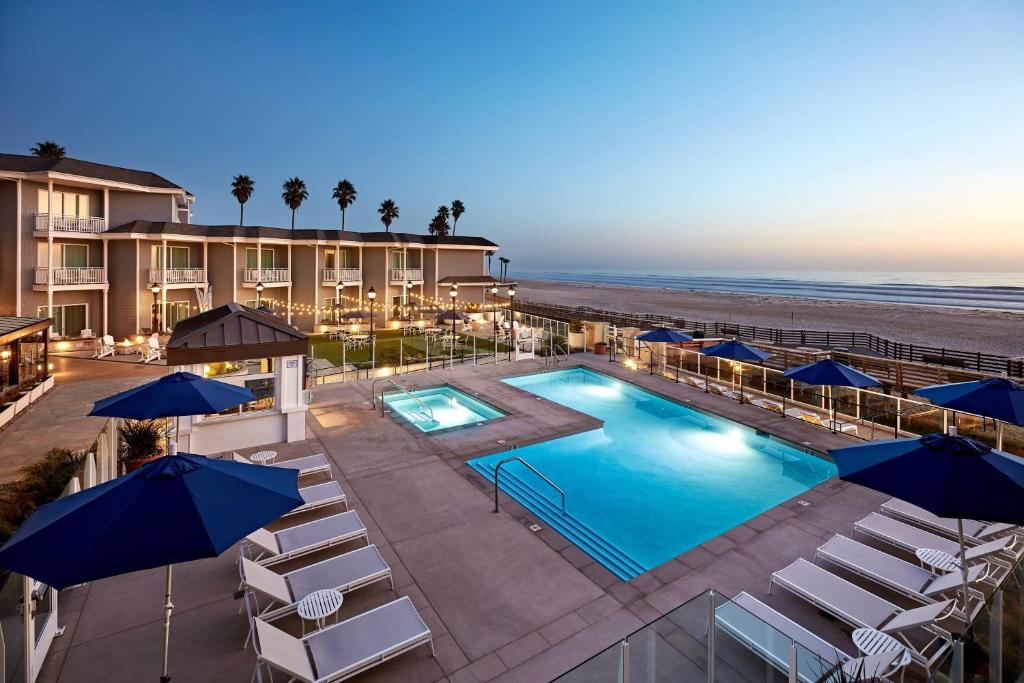 a hotel with a pool and chairs and a beach at Vespera Resort on Pismo Beach, Autograph Collection in Pismo Beach