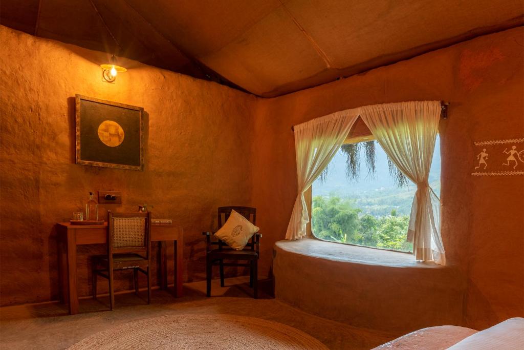 Schlafzimmer mit einem Bett, einem Fenster und einem Tisch in der Unterkunft The Mudhouse Marayoor in Munnar