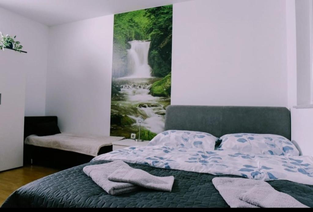 1 dormitorio con 1 cama y una pintura de una cascada en Soba Luić, en Županja