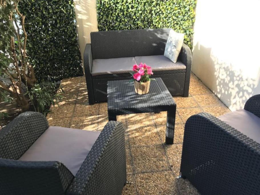 une terrasse avec un canapé et une table fleurie. dans l'établissement Studio rez-de-jardin proche plage et centre ville, à Sainte-Maxime