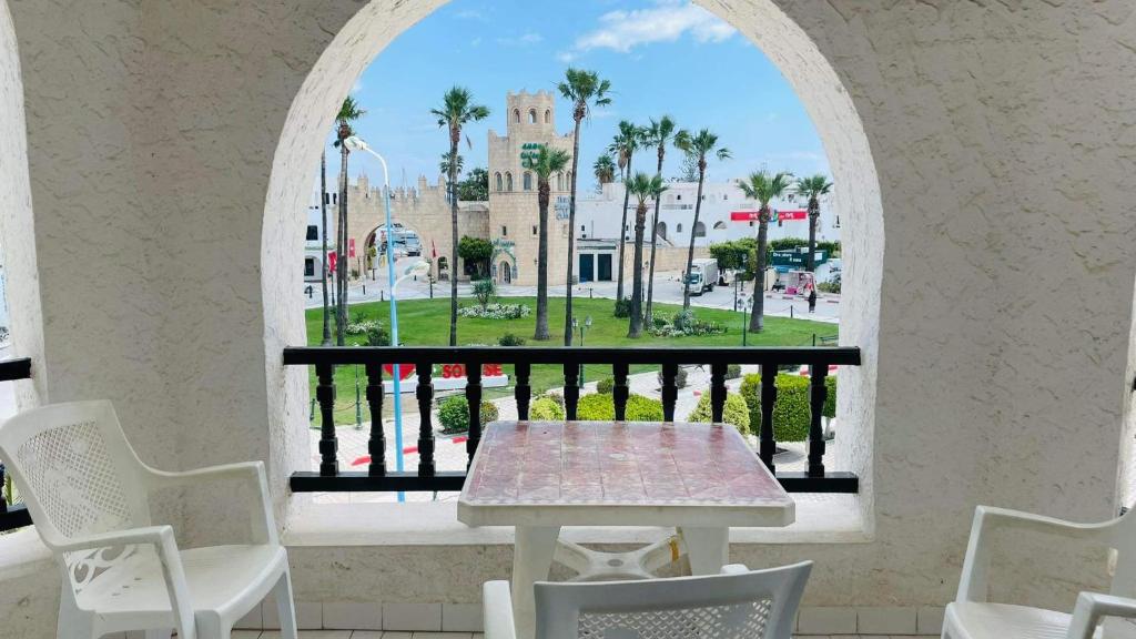 einen Tisch und Stühle in einem Zimmer mit Fenster in der Unterkunft Bungalow S+1 au port de Kantaoui, Sousse. Avec balcon offrant une panorama envoûtant in Sousse