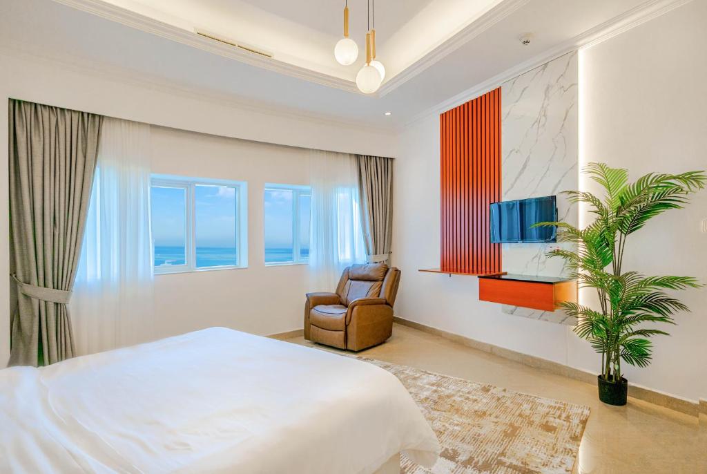 a bedroom with a bed and a chair and a television at Beautiful Al Marjan sea view Apartment in Ras al Khaimah
