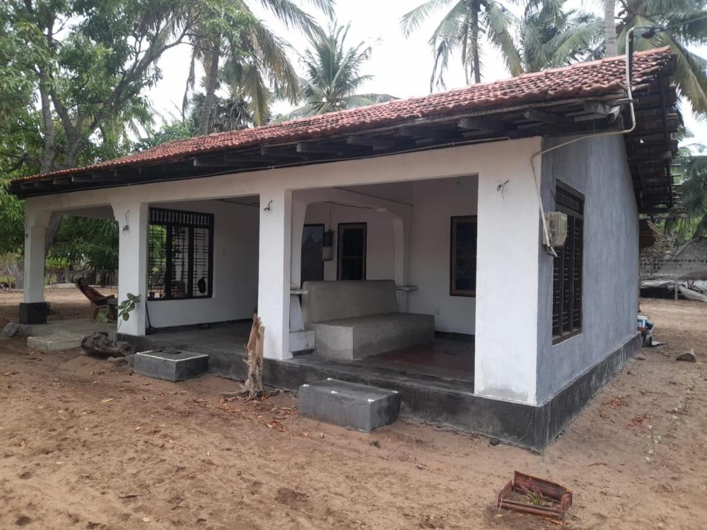 una pequeña casa con un porche en la tierra en School Keen Kite Surf en Kalpitiya
