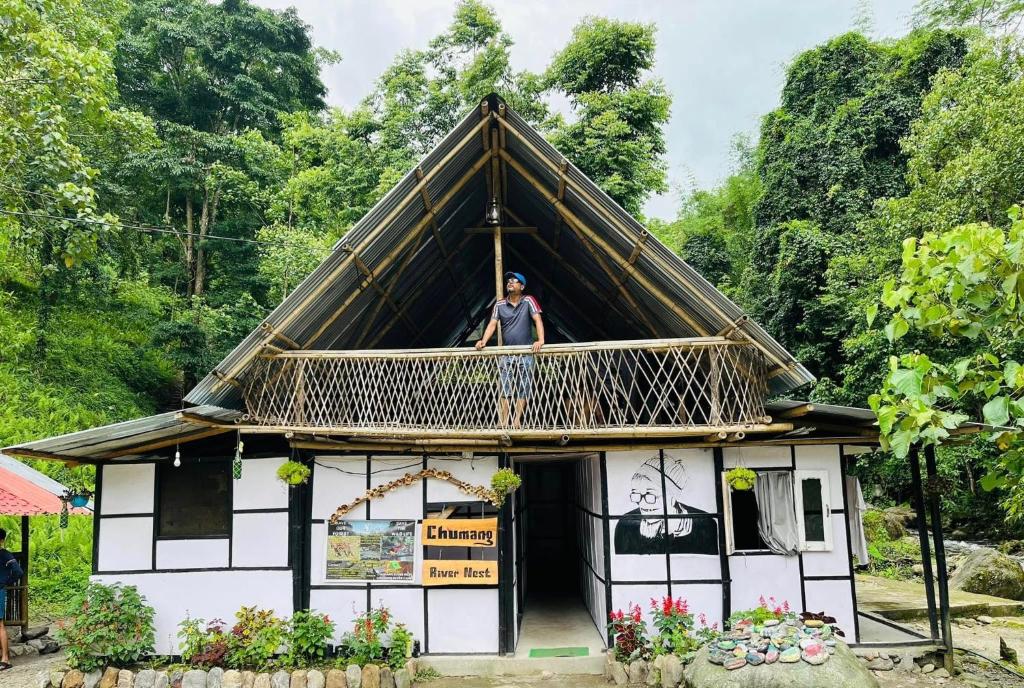 a man standing on the balcony of a house at Chumang River Nest in Thode