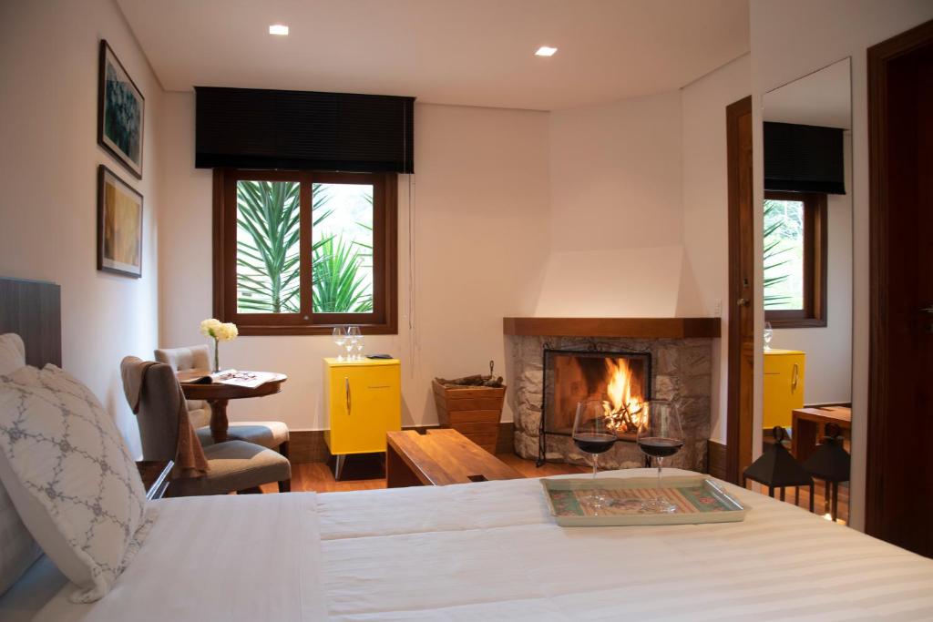 a living room with a bed and a fireplace at Pousada Déllis in Visconde De Maua