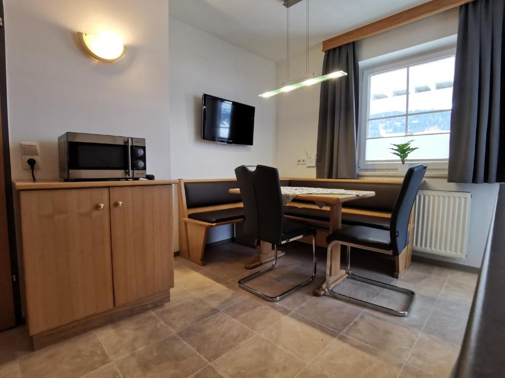 フラッハウにあるGästehaus Amadéのテーブルと椅子、テレビが備わる客室です。