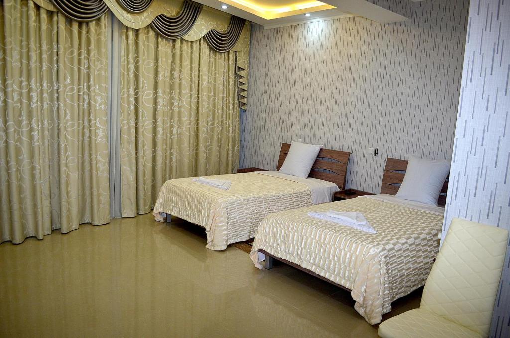 2 letti posti in una stanza con tende di Hotel Okriba a Kutaisi