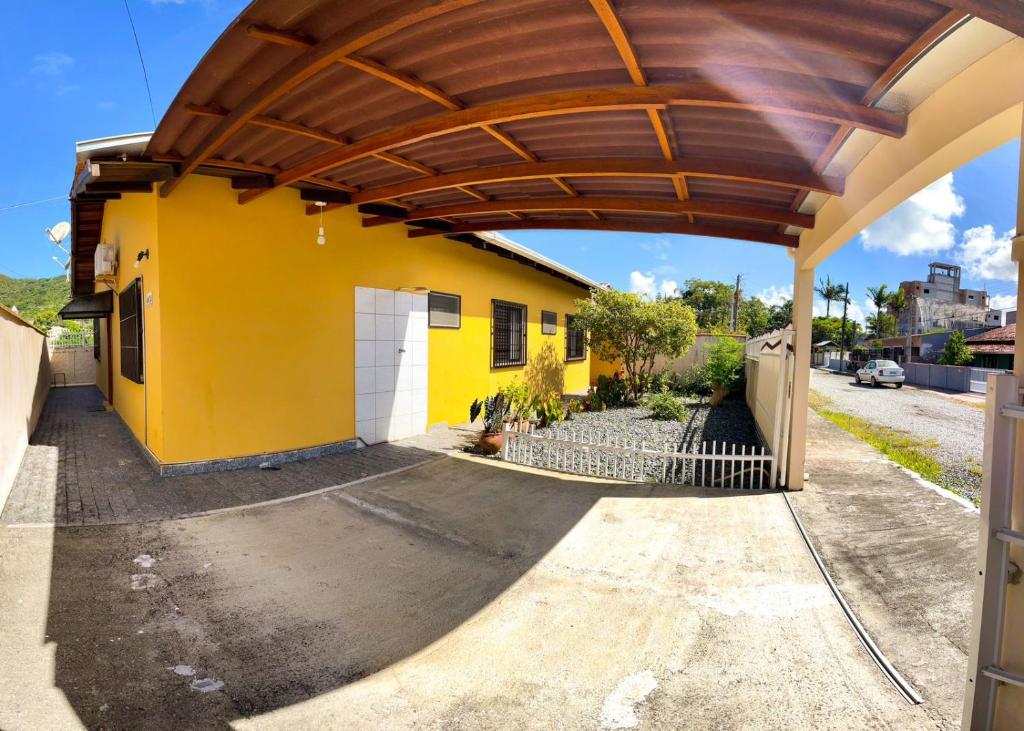 a yellow house with a wooden roof at Hospedagem Vó Lili Vô Ambrósio in Penha