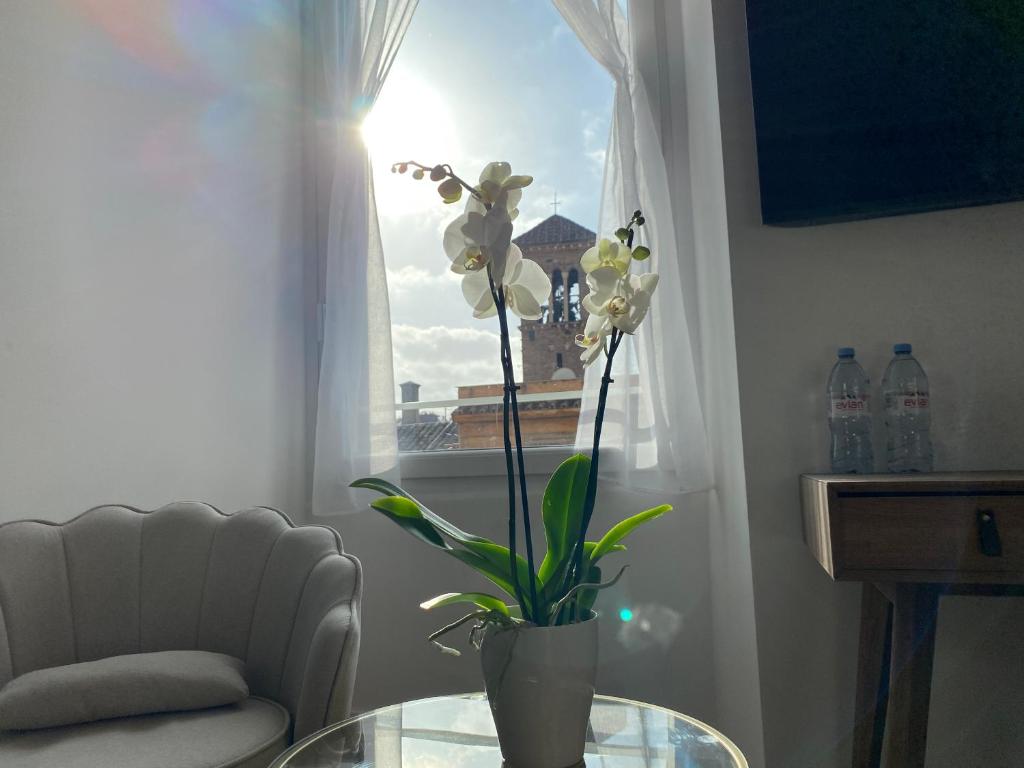 a vase with flowers on a glass table in front of a window at Belltower Elegans in Rome