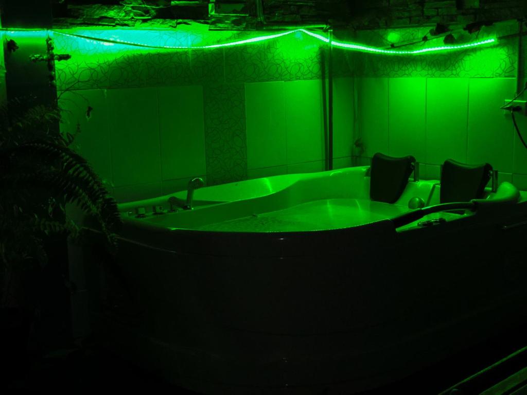 una camera verde con vasca e due sedie di Hospedaje Familiar Valentina a Mera