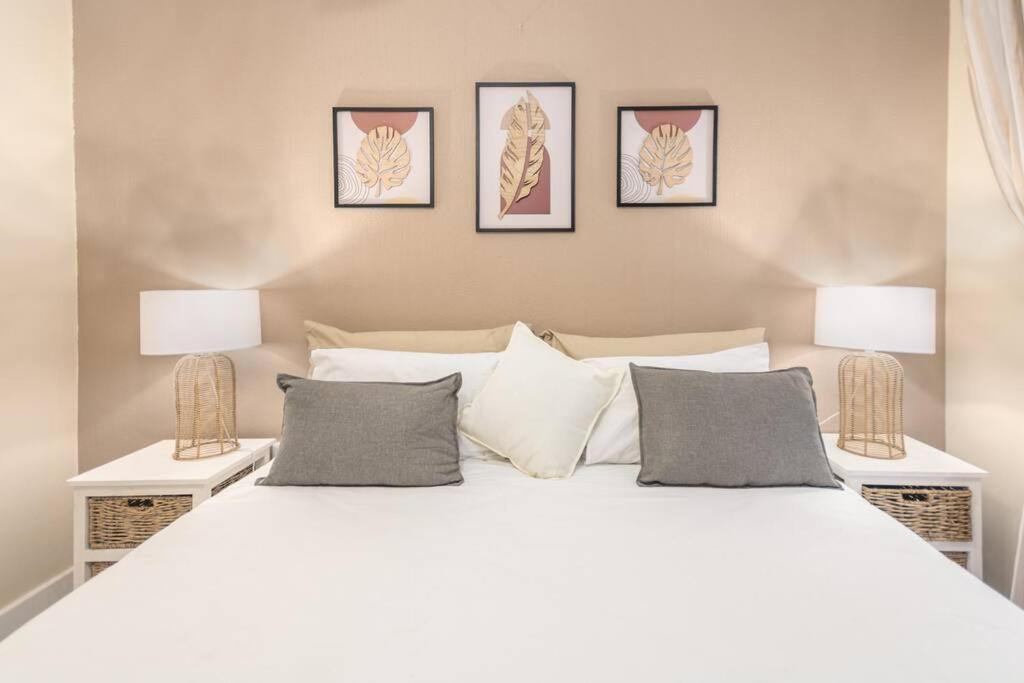 a bedroom with a large white bed with two lamps at Infinity Sunset Beachfront Apartment in Cape Town