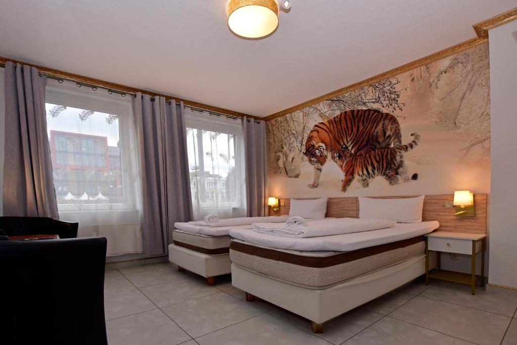 a bedroom with two beds and a painting of a tiger at Ambiente by Next Inn in Hamburg