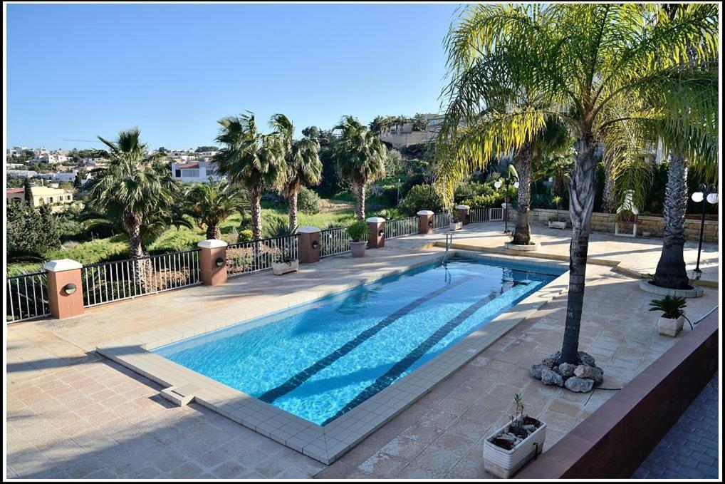 - une piscine avec des palmiers dans un complexe dans l'établissement Villa Lyss apartment 2, à Mellieħa