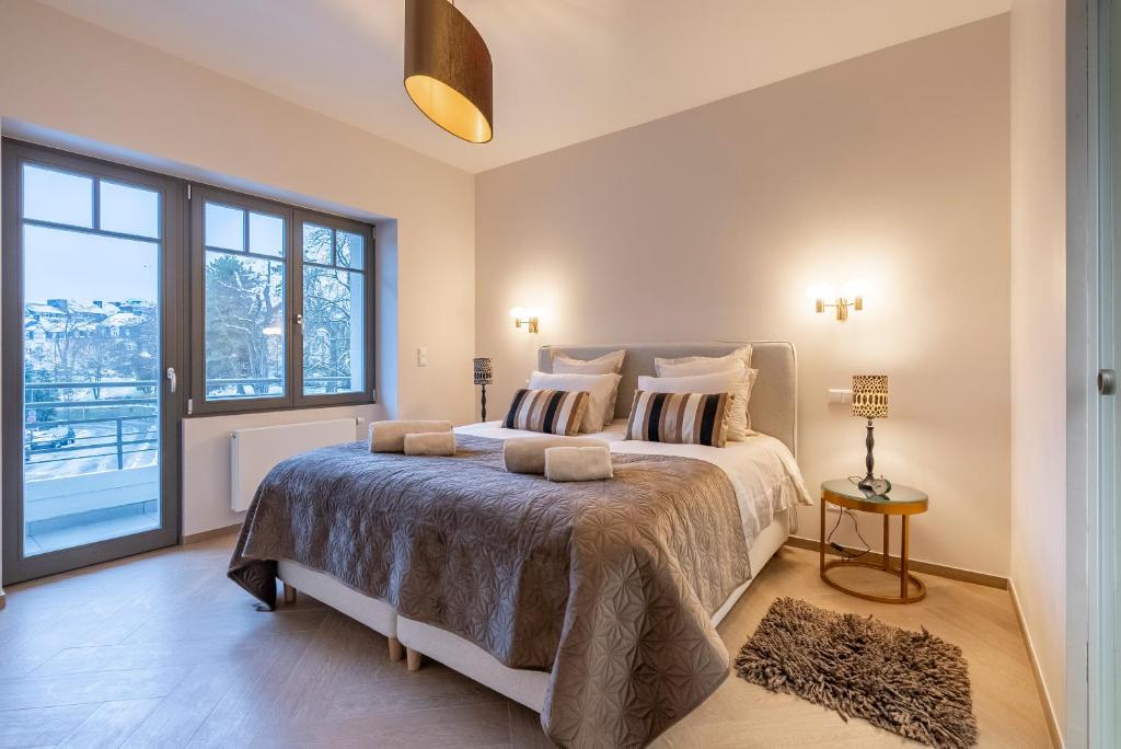 een slaapkamer met een groot bed en een groot raam bij Villa Come in Luxemburg