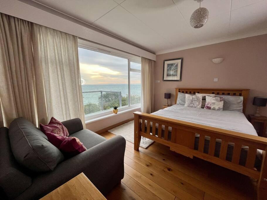 a bedroom with a bed and a couch and a large window at 2 Bedroom Seaview Apartment in Pembrokeshire