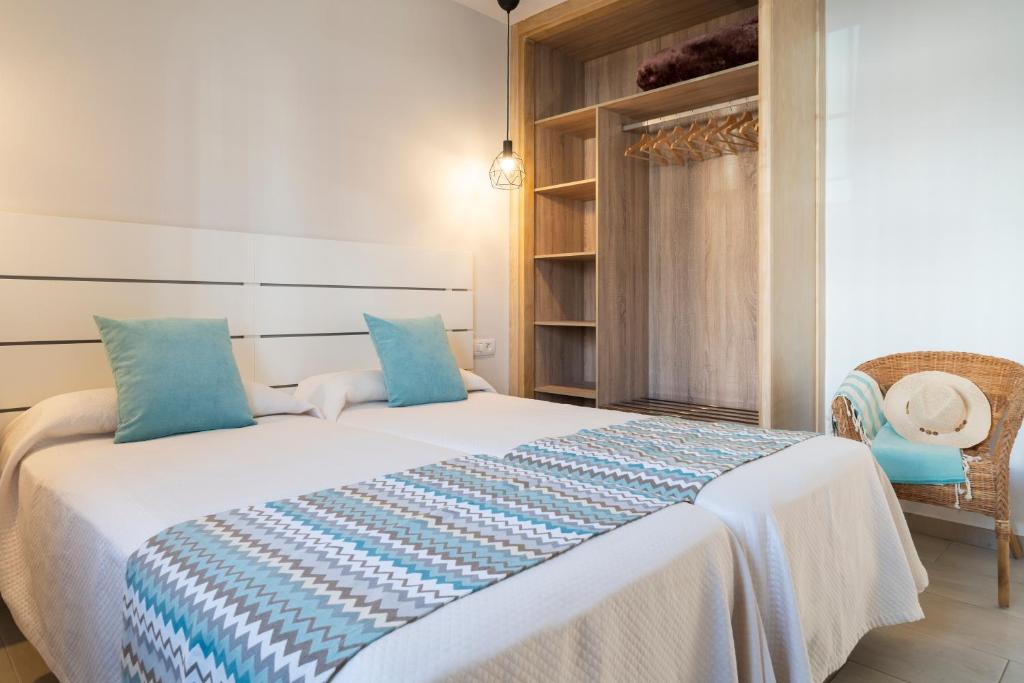 a bedroom with a large white bed with blue pillows at Apartamentos Fayna in Puerto del Carmen