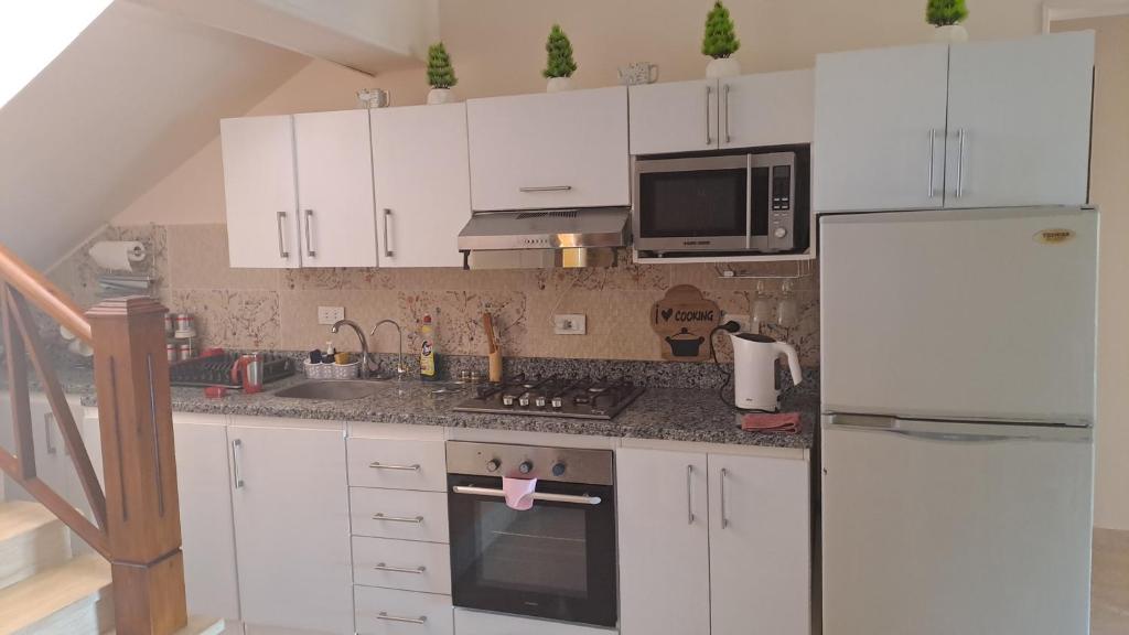 a kitchen with white cabinets and a white refrigerator at Luxury Chalet in Mountain View 2 , El-Sokhna with Sea View , Pool View "Heated Pool" and Garden View Families Only in Ain Sokhna