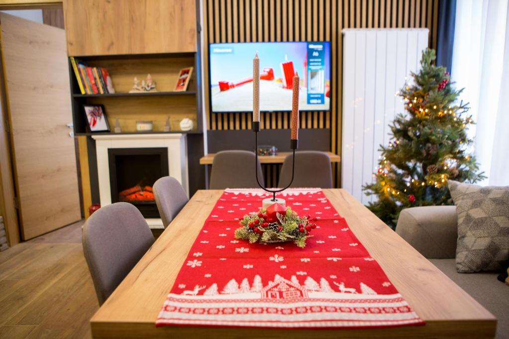 a christmas table with a christmas tree in a room at GreenMont Jahorina in Jahorina