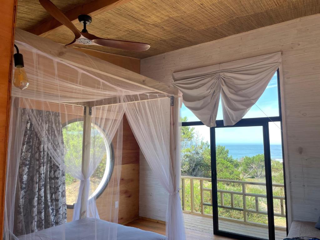 a bedroom with a bed and a large window at Eco Boutique B&B in Punta Del Diablo