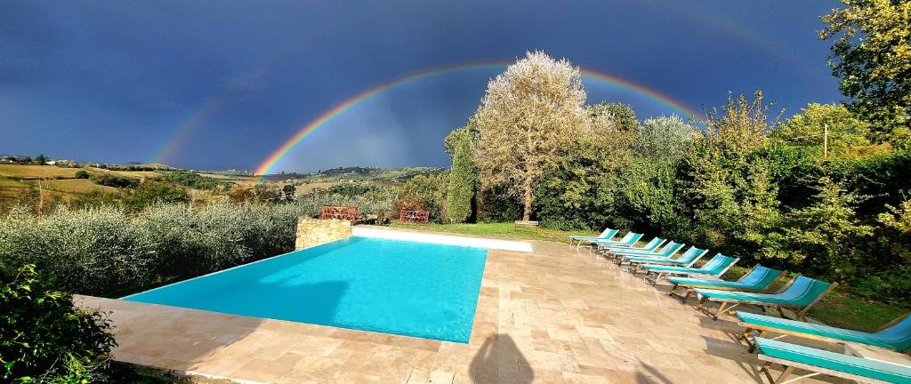 een zwembad met stoelen en een regenboog in de lucht bij La Volpaia 1521 in Barberino di Val dʼElsa