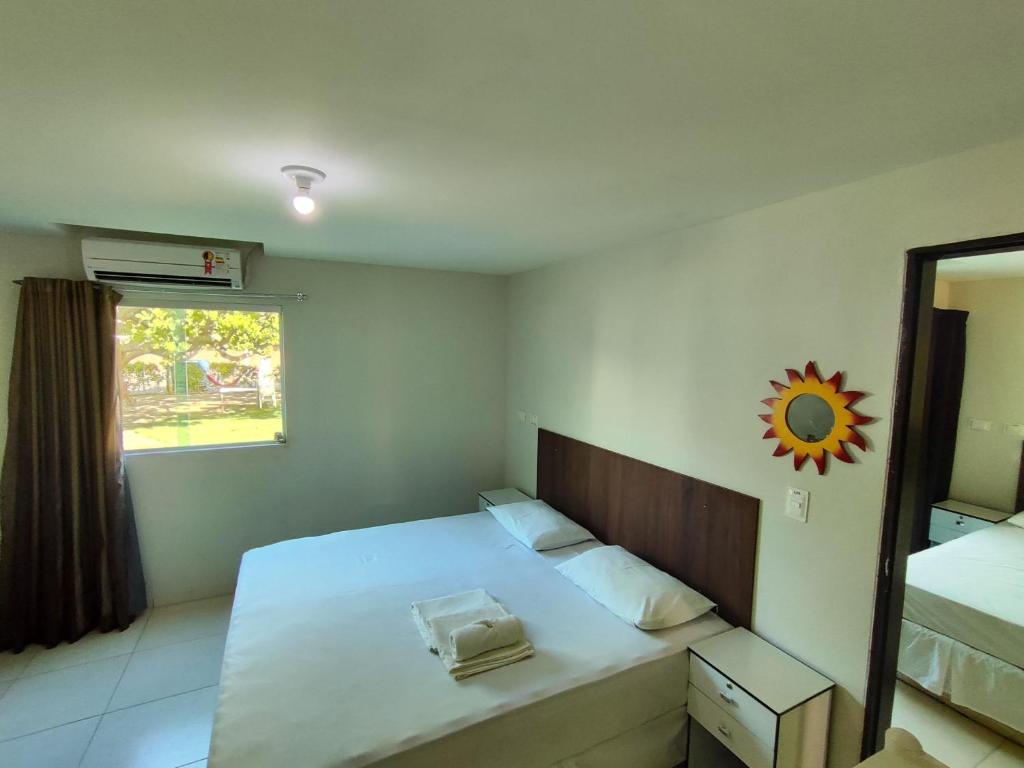 1 dormitorio con cama, espejo y ventana en Divinos Flat Carneiros, en Praia dos Carneiros