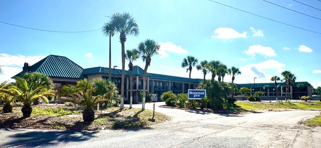 a building with palm trees in front of a street at Rodeway Inn Davenport-Champions Gate in Davenport