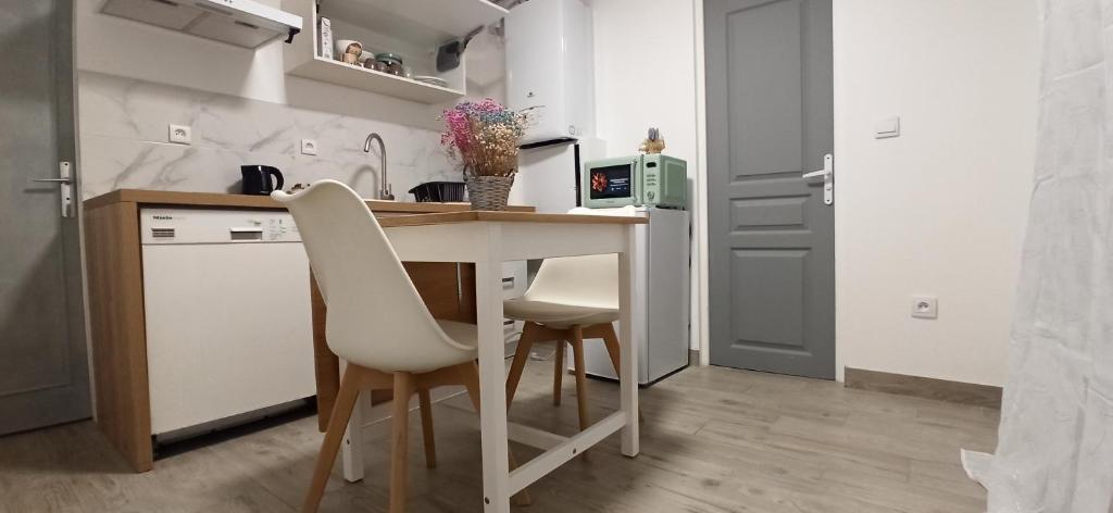 een keuken met een tafel en 2 witte stoelen bij Appartement au rez-de-chaussée avec jardin privé in Margny-lès-Compiègne