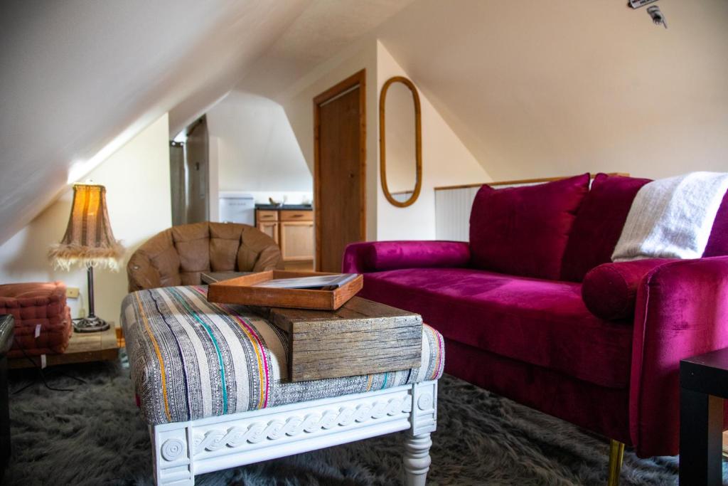 Cozy Tiny Haus Apt في Torrington: غرفة معيشة مع أريكة أرجوانية وطاولة