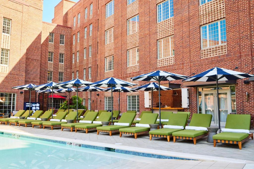 a row of chairs and umbrellas next to a pool at The Alida, Savannah, a Tribute Portfolio Hotel in Savannah