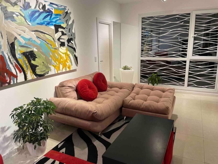 uma sala de estar com um sofá castanho com almofadas vermelhas em Depto Disney en MDP em Mar del Plata