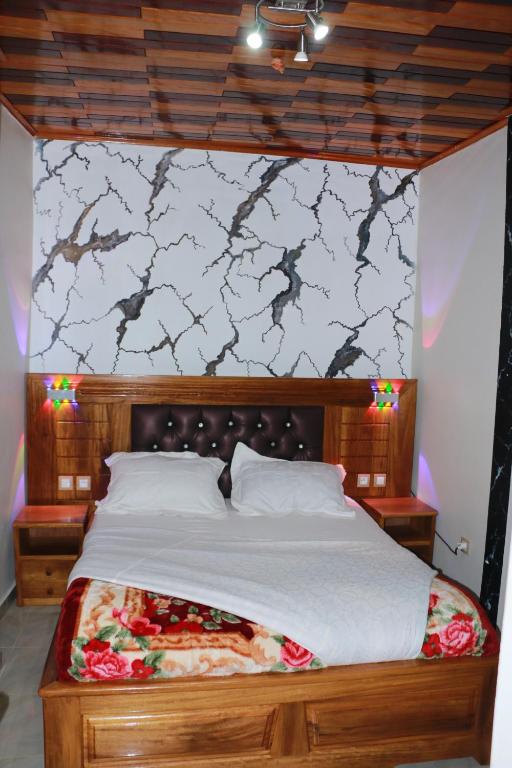 a bedroom with a large bed with a wooden headboard at DEUDJUI HOTEL in Bafang