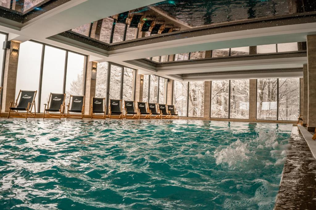 una piscina d'acqua in una stanza con sedie di Milmari Apartments FREE SPA & PARKING Kopaonik a Kopaonik