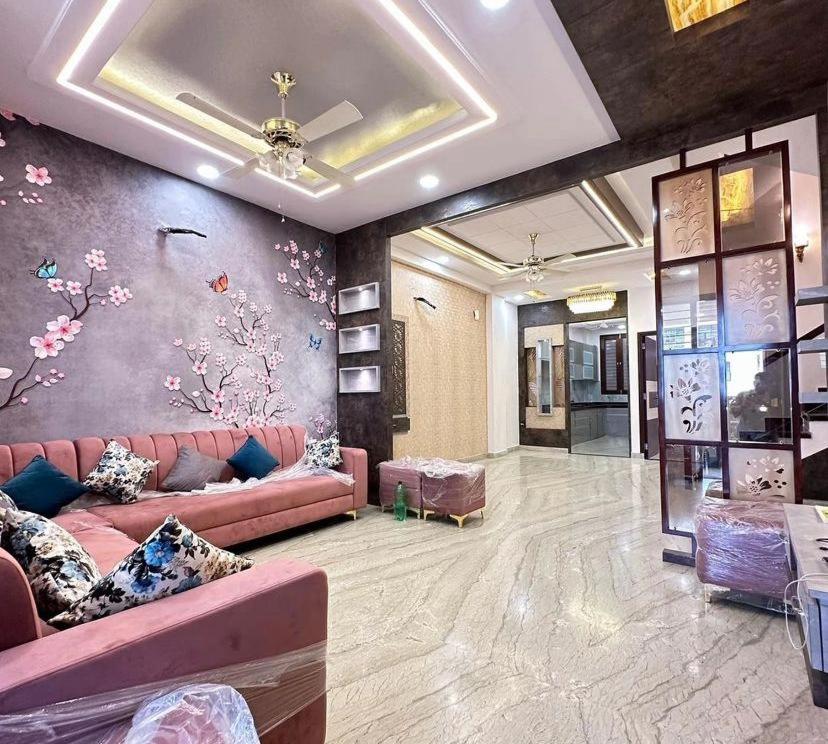 a living room with a pink couch and flowers on the wall at FIRSTHOUSE VILLA@BATU FERRINGHI in Batu Ferringhi