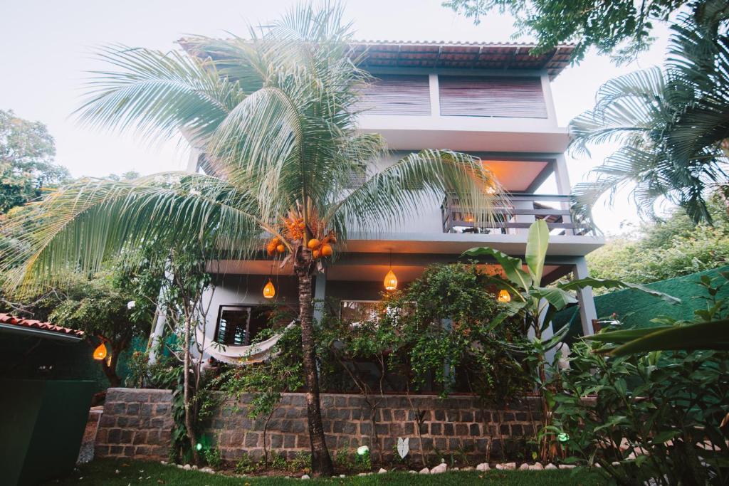 a palm tree in front of a house at La Serena Hostel in Pipa