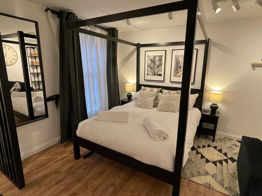 een slaapkamer met een hemelbed en een spiegel bij Ultra Modern Studio Apartment, in Central Exeter in Exeter